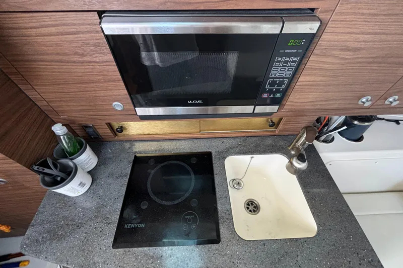  Yacht Photos Pics Compact kitchen in 2020 Boston Whaler 325 Conquest Pilothouse with microwave, stove, and sink.