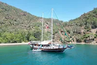 Custom 2007 GULET yacht anchored in a scenic bay with lush green hills.