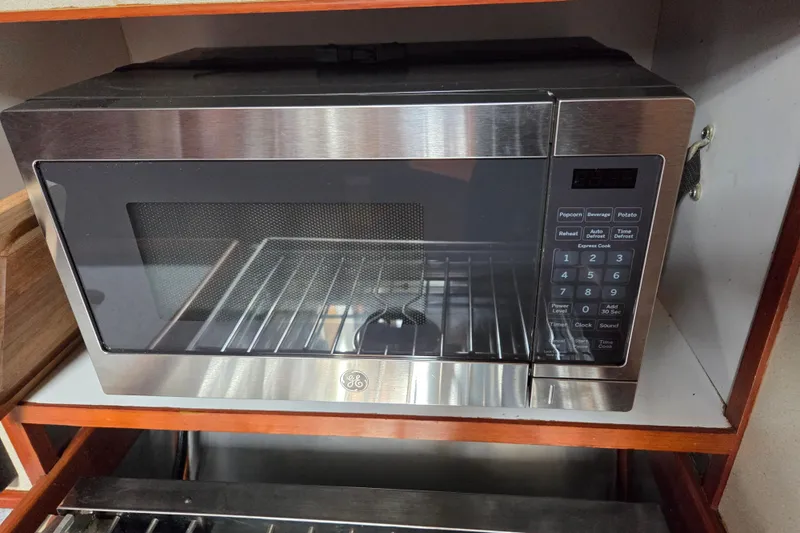 Callahan Yacht Photos Pics Stainless steel microwave oven with digital keypad in a wooden cabinet.