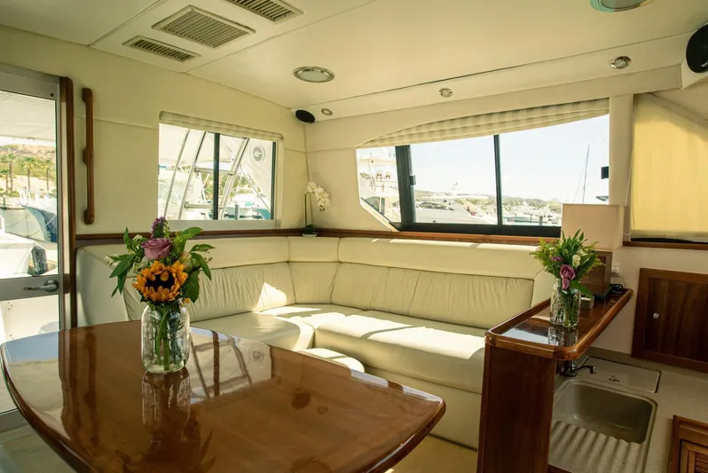 Skiesta Yacht Photos Pics Interior of 2002 Riviera 40 Flybridge yacht with cream leather seating and wooden table.