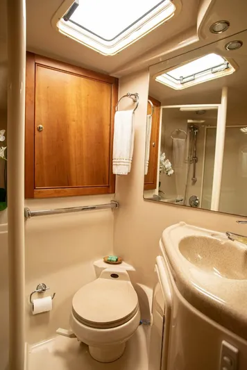 Skiesta Yacht Photos Pics 2002 Riviera 40 Flybridge yacht bathroom with skylight, wooden cabinet, and modern fixtures.