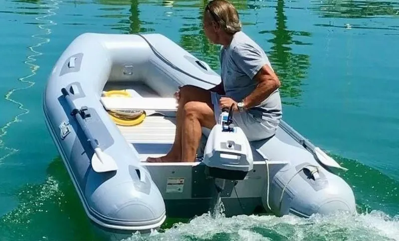 Skiesta Yacht Photos Pics Person operating inflatable boat on water, Riviera 40 Flybridge 2002 in background.