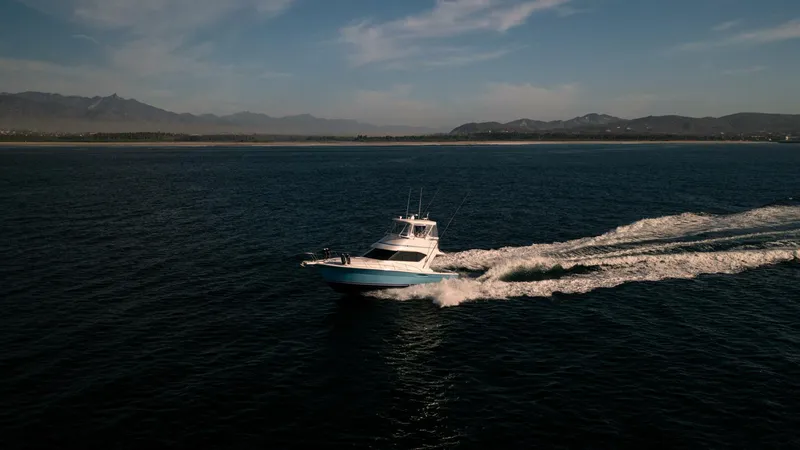 Skiesta Yacht Photos Pics 2002 Riviera 40 Flybridge cruising on open water with scenic mountain backdrop.