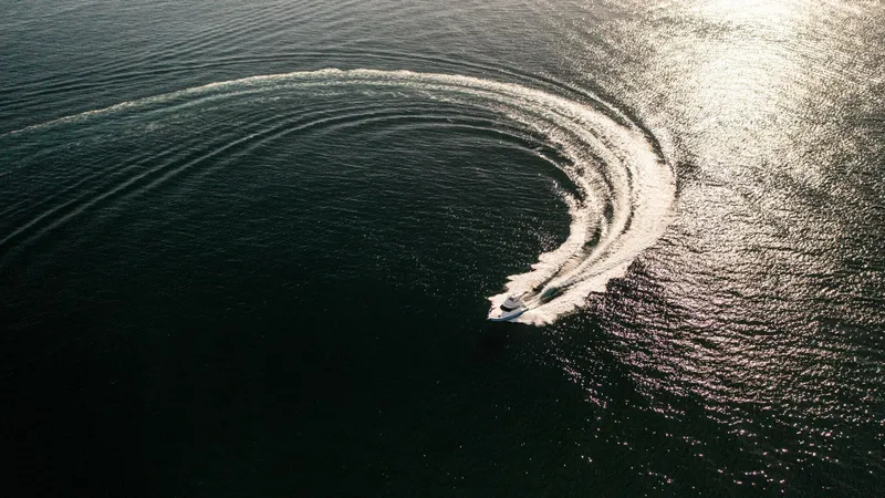 Skiesta Yacht Photos Pics Aerial view of 2002 Riviera 40 Flybridge making a sharp turn on open water.