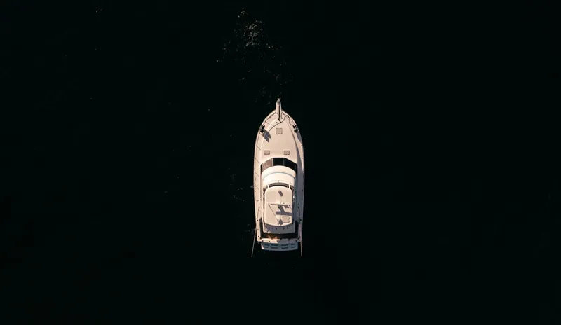 Skiesta Yacht Photos Pics Aerial view of a 2002 Riviera 40 Flybridge yacht cruising on dark waters.