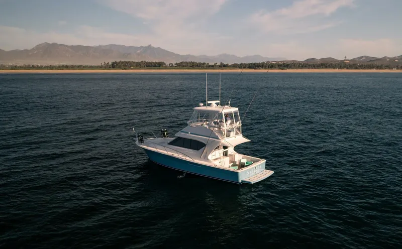 Skiesta Yacht Photos Pics 2002 Riviera 40 Flybridge yacht cruising on open water with scenic mountain backdrop.