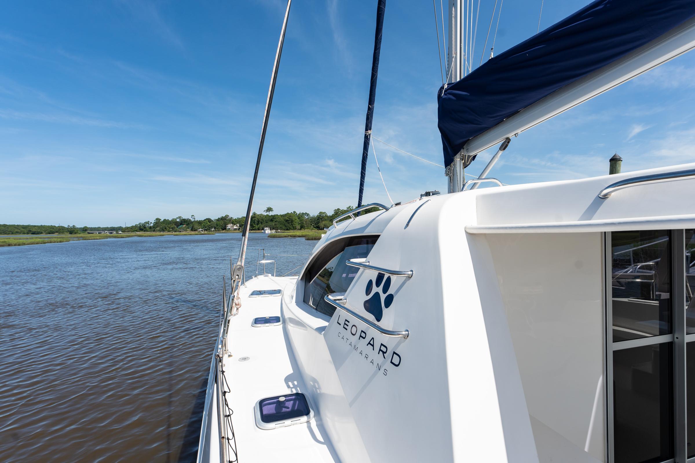 2016 Leopard 44 Owners Version catamaran sailing on a calm river under a clear blue sky.