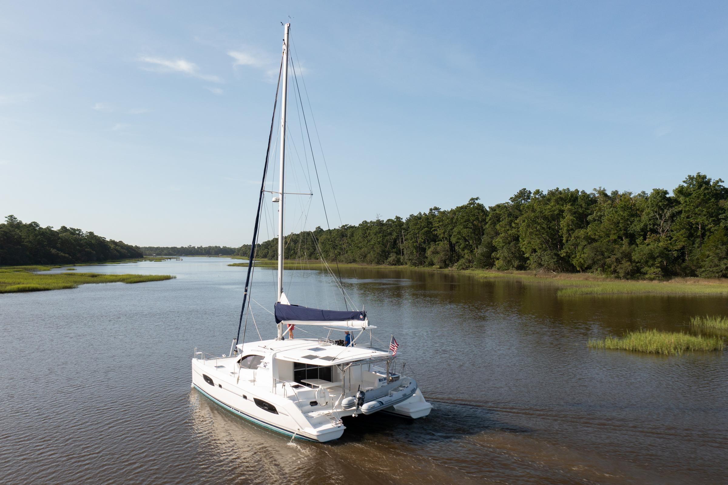 2016 Leopard 44 Owners Version catamaran sailing on a serene river with lush greenery.