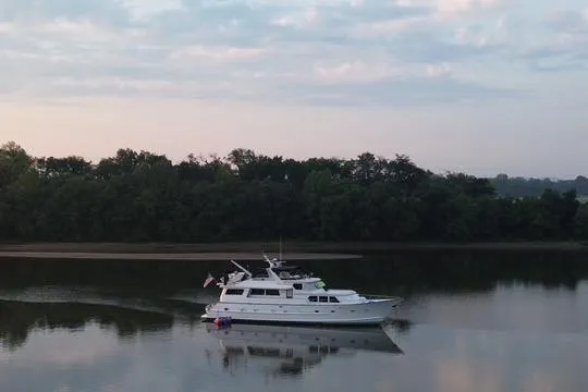 Sweet Freedom Yacht Photos Pics 1984 Broward CPMY Raised Pilothouse yacht cruising on calm river at sunrise.