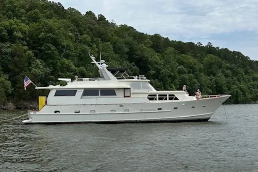 Sweet Freedom Yacht Photos Pics 1984 Broward CPMY Raised Pilothouse yacht on a serene lake with lush green forest backdrop.