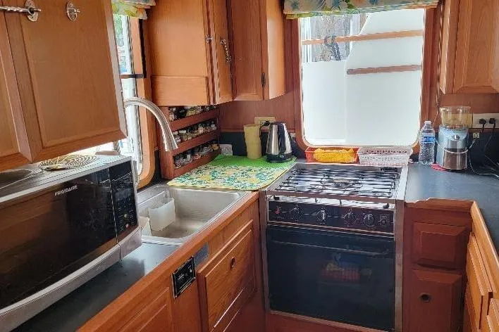 Bedouin Yacht Photos Pics 1998 DeFever 44 Sundeck Trawler kitchen with wooden cabinets, stove, and microwave.
