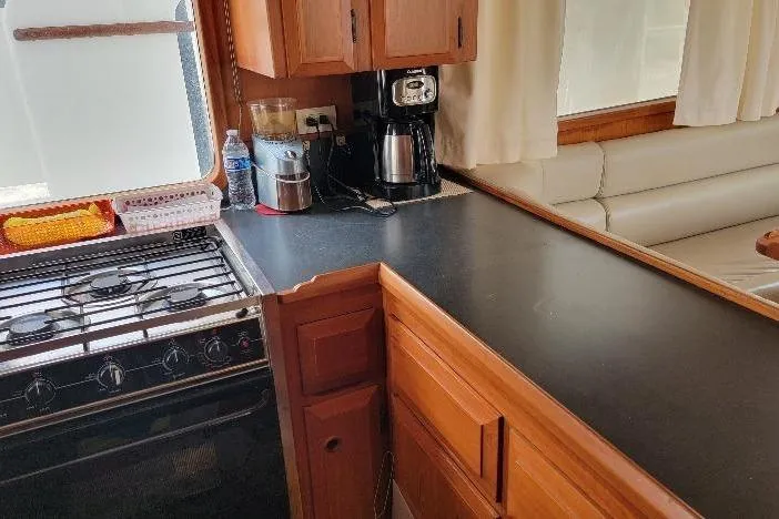 Bedouin Yacht Photos Pics 1998 DeFever 44 Sundeck Trawler kitchen with stove, counter, and seating area.