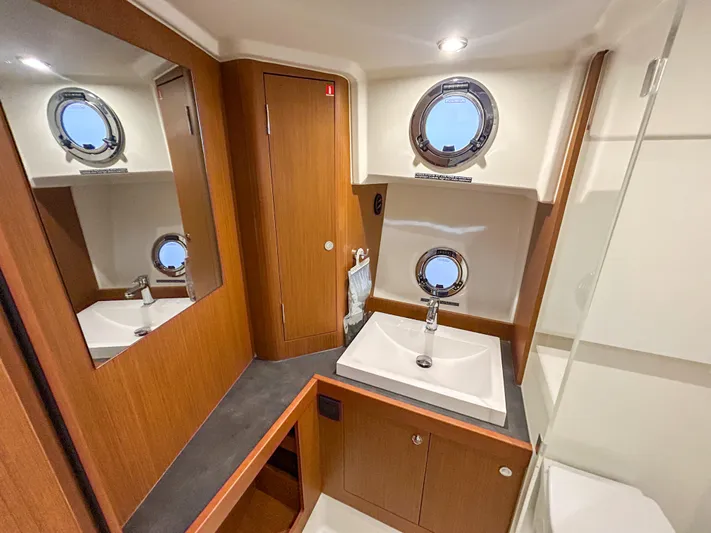  Yacht Photos Pics Luxurious bathroom in 2023 Beneteau Swift Trawler 35 with modern fixtures and porthole windows.