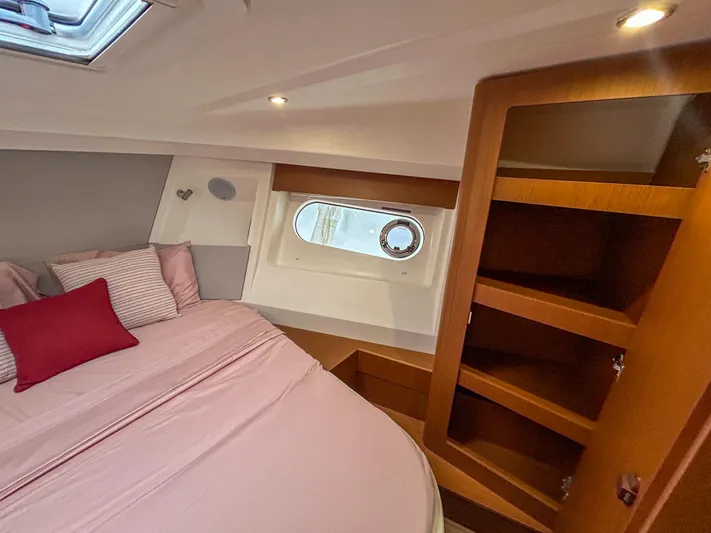  Yacht Photos Pics Cozy bedroom interior of 2023 Beneteau Swift Trawler 35 with wooden shelves and porthole window.
