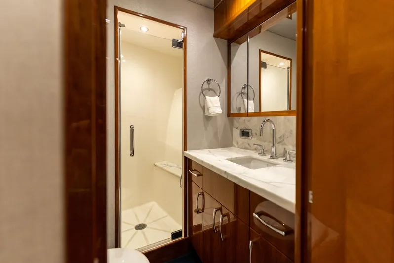 Resilient Yacht Photos Pics Luxurious bathroom in 2018 Hatteras GT70 yacht with marble countertop and glass shower.
