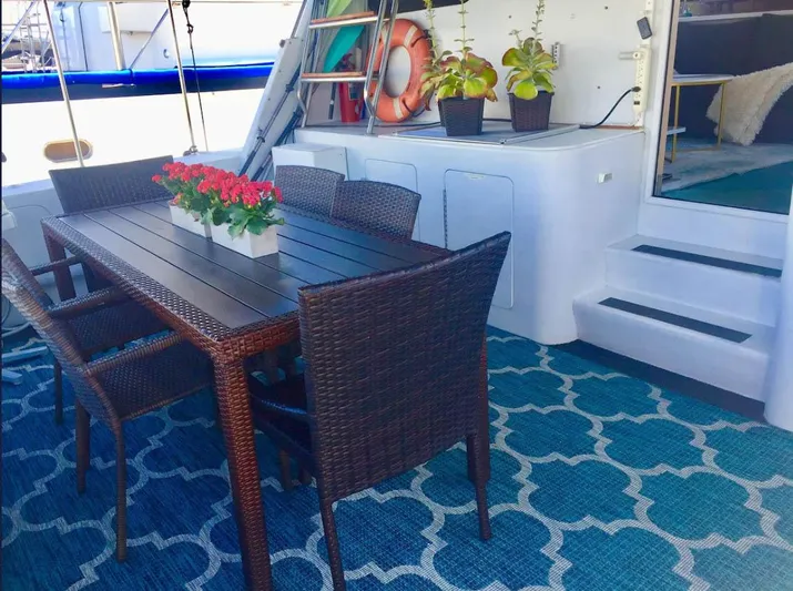 The West Star Yacht Photos Pics Outdoor dining area on Shaw 57 yacht, featuring wicker chairs and floral centerpiece, 1994 model.