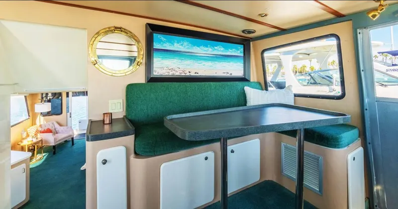 The West Star Yacht Photos Pics Interior of a 1994 Shaw 57 boat with green seating and a beach painting.