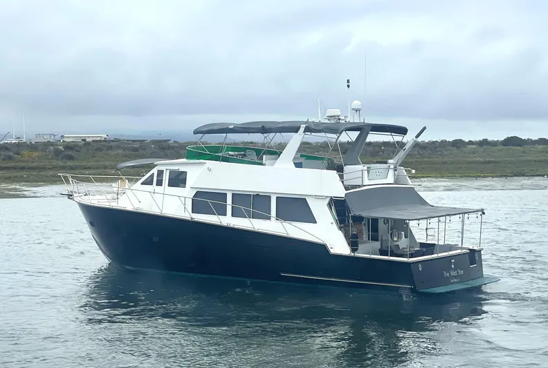 The West Star Yacht Photos Pics Shaw 57 yacht from 1994 on calm waters, featuring a sleek design and spacious deck.