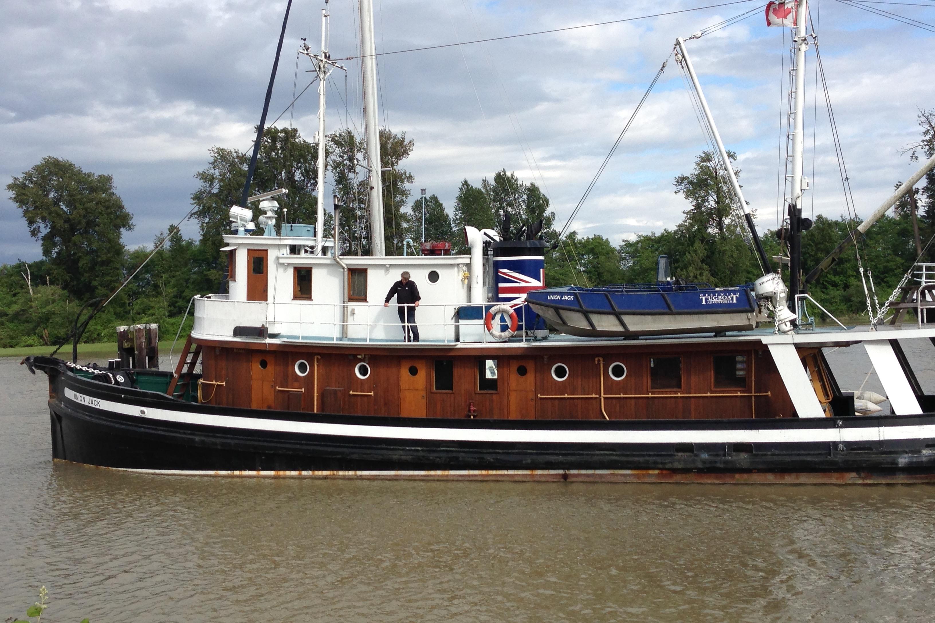 Vintage 1941 McKenzie Barge & Derrick Co. Ltd tugboat on a river, featuring wooden details.