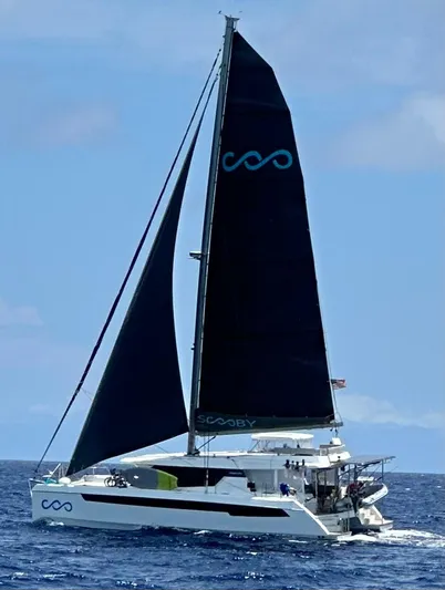 Scooby Yacht Photos Pics Leopard 50 catamaran sailing on open sea, 2022 model, with black sails and blue logo.