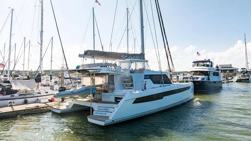 Scooby Yacht Photos Pics 2022 Leopard 50 catamaran docked at marina, surrounded by other boats, sunny day.