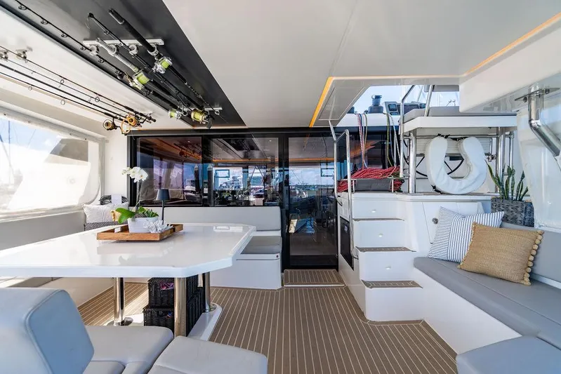 Scooby Yacht Photos Pics Luxurious 2022 Leopard 50 yacht interior with seating, dining table, and fishing rods.
