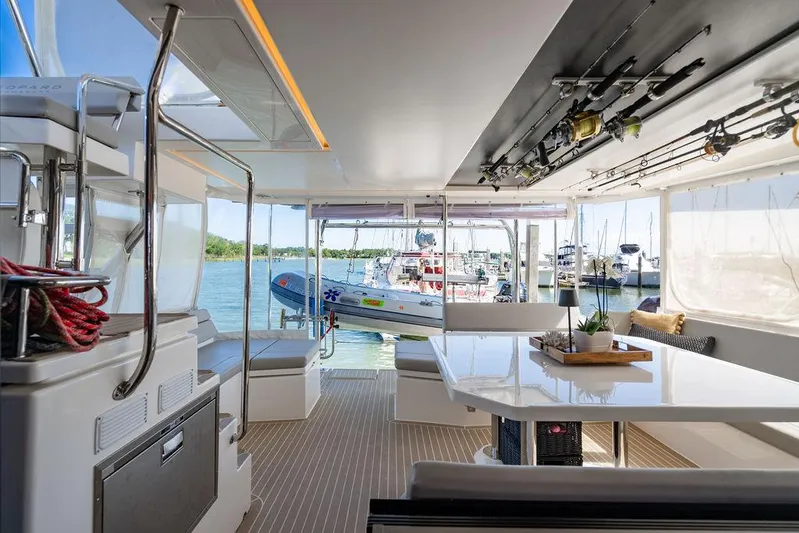 Scooby Yacht Photos Pics Luxurious 2022 Leopard 50 yacht interior with fishing rods, spacious seating, and marina view.