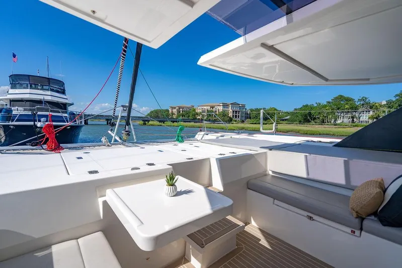 Scooby Yacht Photos Pics Luxurious Leopard 50 yacht interior with seating, table, and scenic waterfront view, 2022 model.