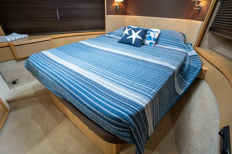 Luna Yacht Photos Pics Luxurious 2009 Princess V62 yacht bedroom with blue-striped bedding and decorative pillows.