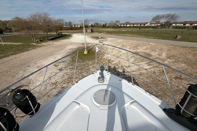  Yacht Photos Pics Bow view of 2003 Carver 564 Cockpit Motor Yacht on land, surrounded by trees.