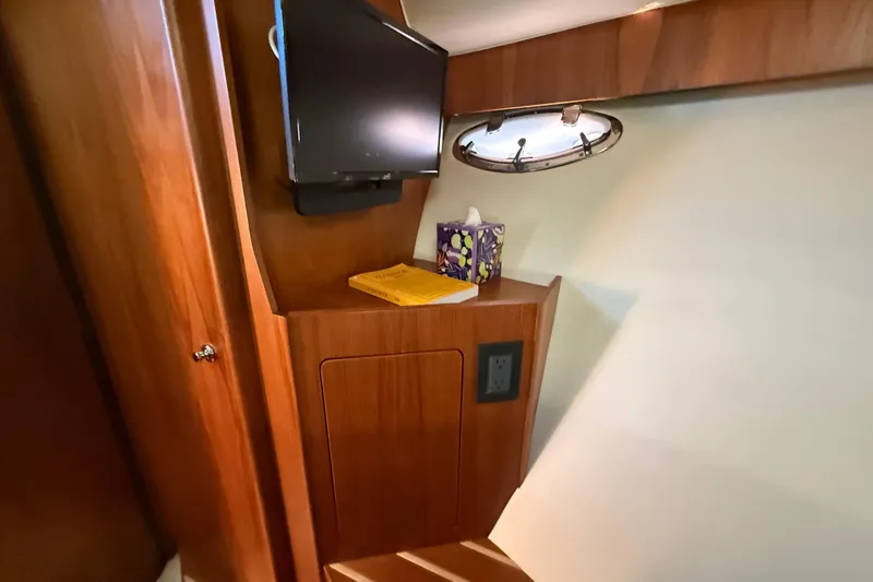  Yacht Photos Pics Interior of 2012 Tiara Yachts 3100 Coronet with TV, porthole, and wooden cabinetry.