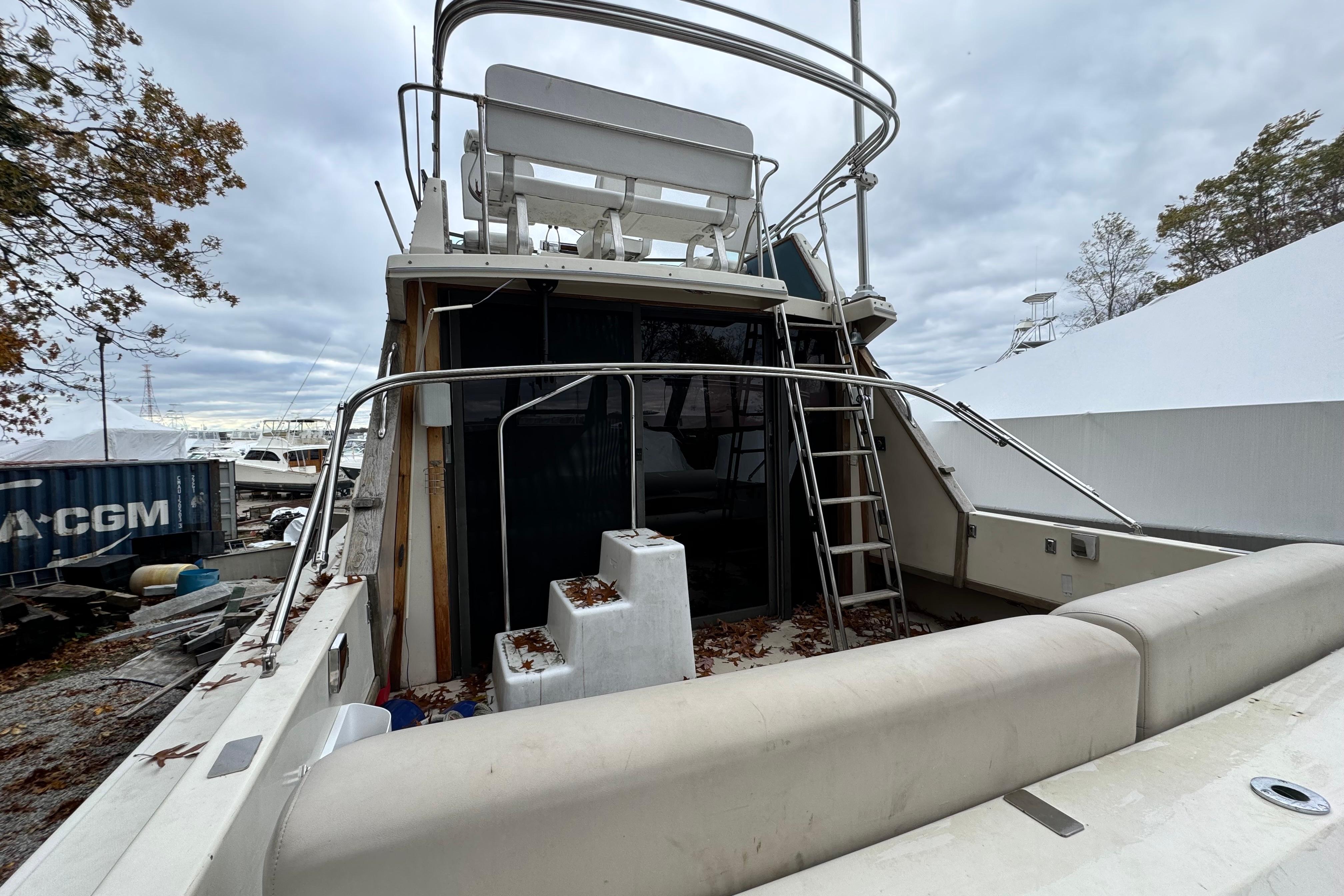 1986 Stamas Flybridge Sedan boat with ladder and seating, docked outdoors.