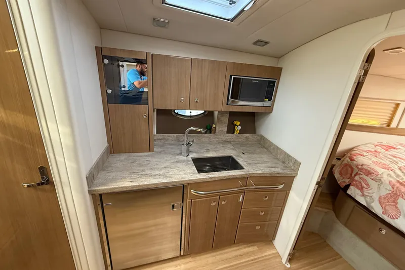  Yacht Photos Pics 2016 Formula 37 Performance Cruiser interior kitchen with sink, microwave, and wooden cabinetry.
