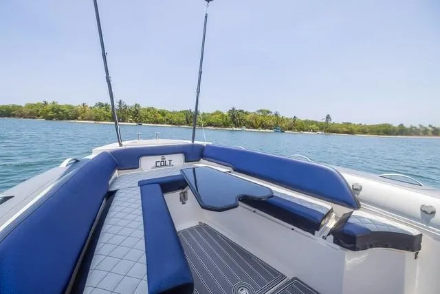  Yacht Photos Pics 2018 RIB CVL Colt 35 boat interior with blue seating, on calm water near a lush shoreline.
