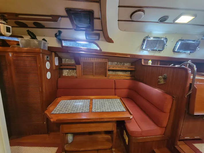 Searcher Yacht Photos Pics Cozy interior of 1981 Tayana Vancouver 42 sailboat with wooden furnishings and red seating.