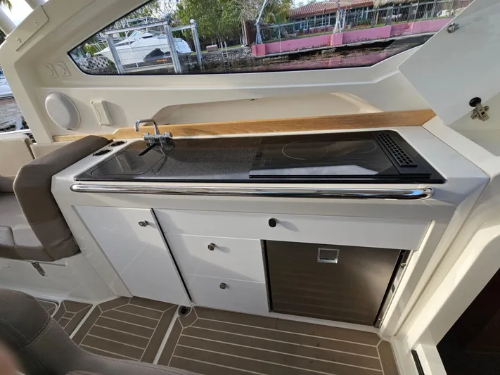  Yacht Photos Pics 2020 Nimbus Weekender 9 boat interior with kitchenette, featuring sink, stove, and storage cabinets.