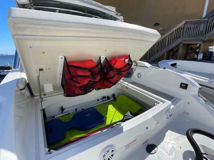  Yacht Photos Pics 2021 Cobalt 30SC Outboard boat storage compartment with colorful gear and red mesh bags.