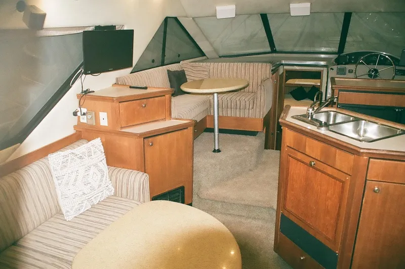 Mokikem Yacht Photos Pics Interior of 1995 Bayliner 3988 Command Bridge Motoryacht with seating, table, and kitchenette.