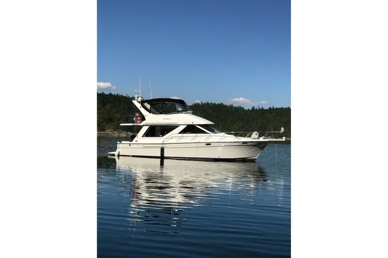 Mokikem Yacht Photos Pics 1995 Bayliner 3988 Command Bridge Motoryacht on calm water, clear sky background.