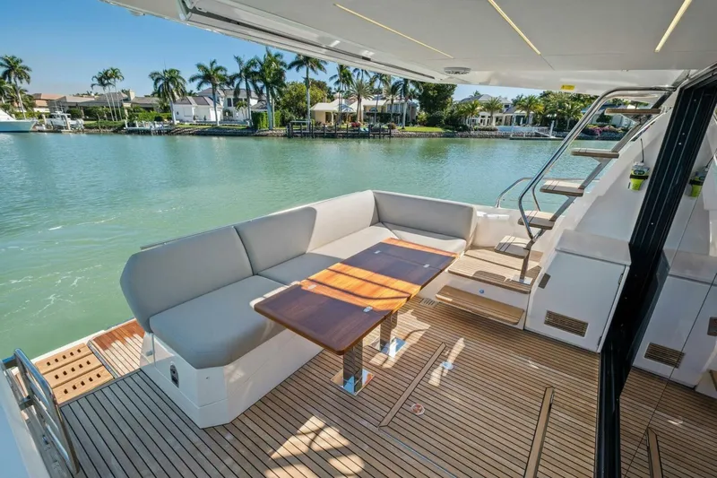 No Patience Yacht Photos Pics Luxurious 2022 Prestige 520 yacht deck with seating, table, and scenic waterfront view.