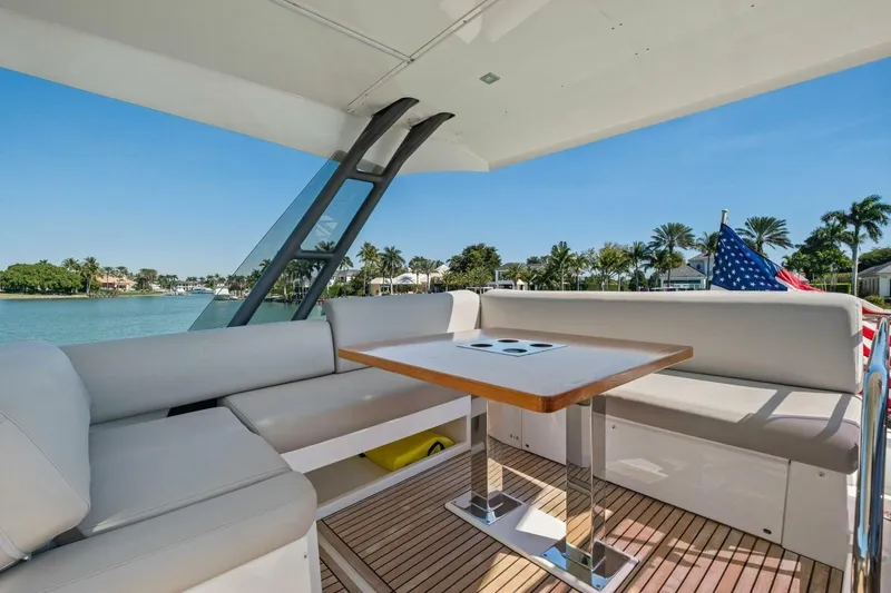 No Patience Yacht Photos Pics Luxurious 2022 Prestige 520 yacht deck with seating, table, and scenic waterfront view.