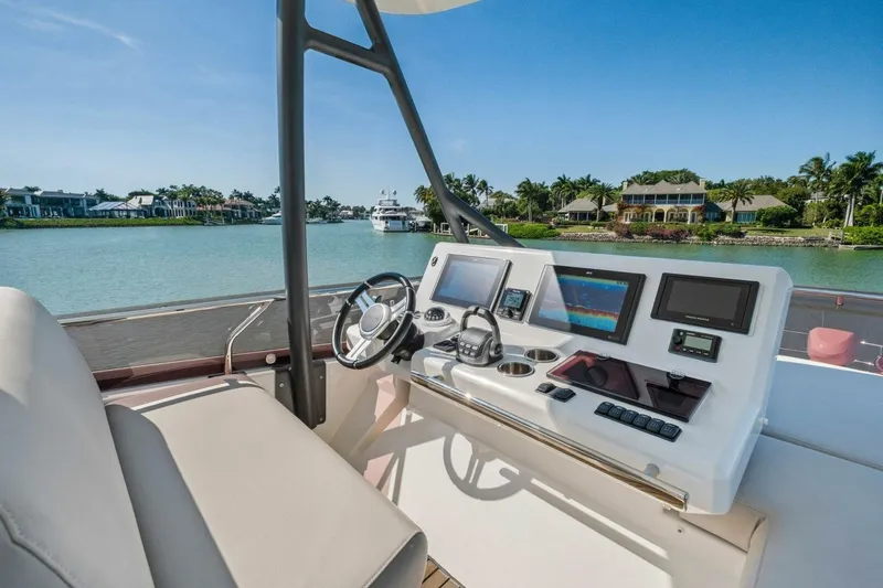 No Patience Yacht Photos Pics Helm of 2022 Prestige 520 yacht with modern navigation equipment, overlooking serene waterfront homes.