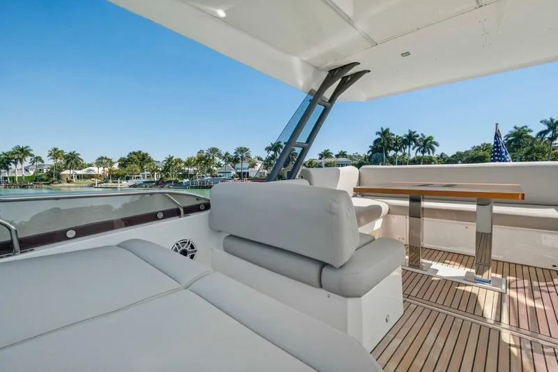 No Patience Yacht Photos Pics Luxurious 2022 Prestige 520 yacht deck with seating, table, and scenic waterfront view.