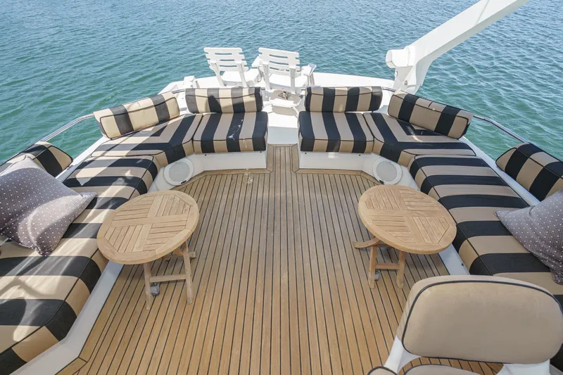 Shady Lady Yacht Photos Pics Luxurious 1995 Navigator Classic yacht deck with striped seating and wooden tables on open water.