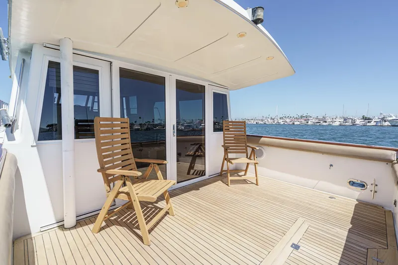 Shady Lady Yacht Photos Pics Deck of 1995 Navigator Classic yacht with wooden chairs, overlooking marina.
