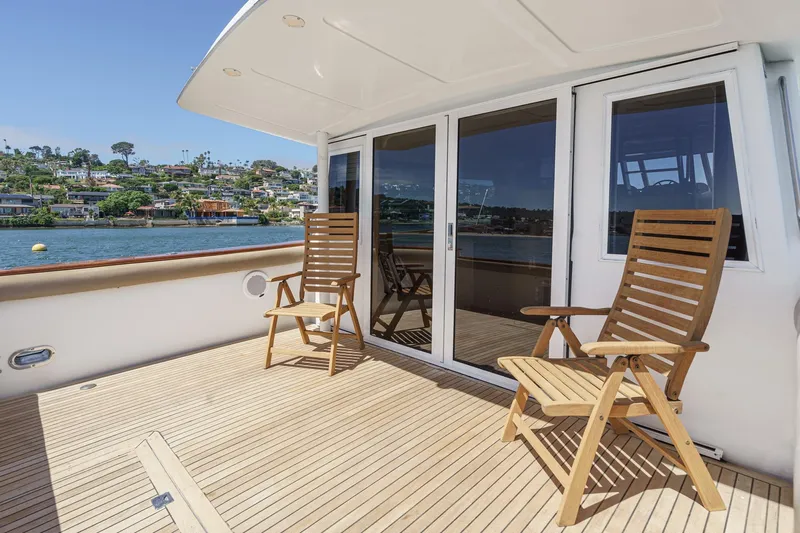 Shady Lady Yacht Photos Pics Deck of 1995 Navigator Classic yacht with wooden chairs, overlooking scenic waterfront homes.