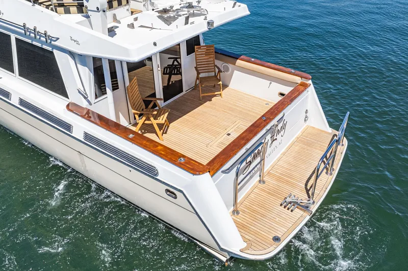 Shady Lady Yacht Photos Pics 1995 Navigator Classic yacht with wooden deck, chairs, and ladder on calm water.