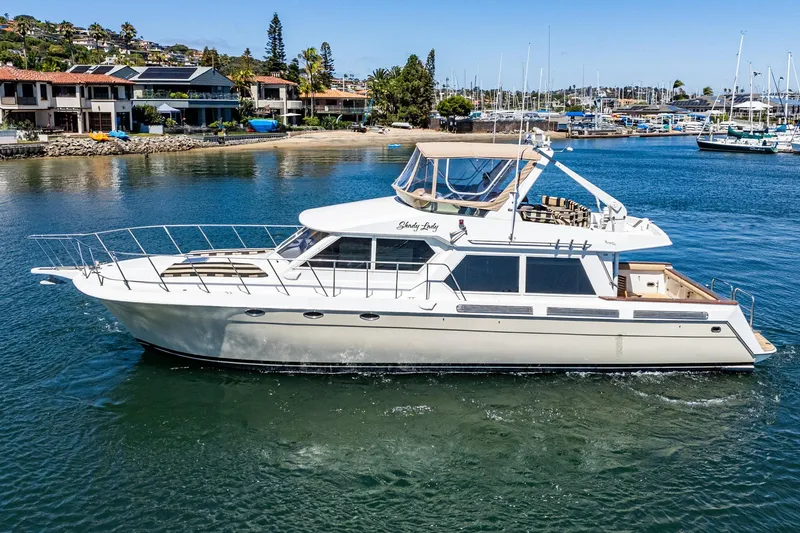 Shady Lady Yacht Photos Pics 1995 Navigator Classic yacht cruising near marina, surrounded by waterfront homes and sailboats.