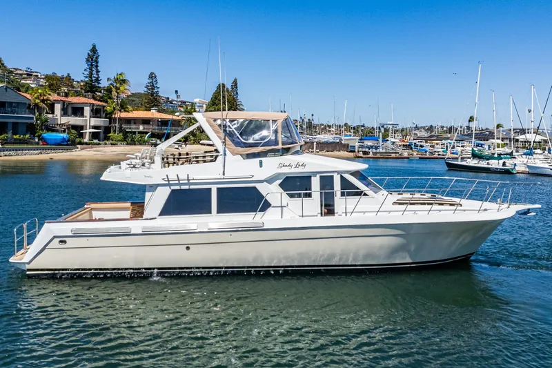 Shady Lady Yacht Photos Pics 1995 Navigator Classic yacht on calm water near marina, clear blue sky background.