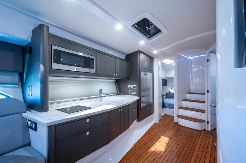 Karey Lee Yacht Photos Pics Luxurious 2024 Intrepid 477 Evolution yacht interior with modern kitchen and wooden flooring.
